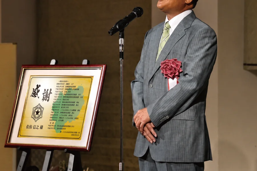 自治体職員が贈られた退職祝い・退職記念品を前に挨拶する場面