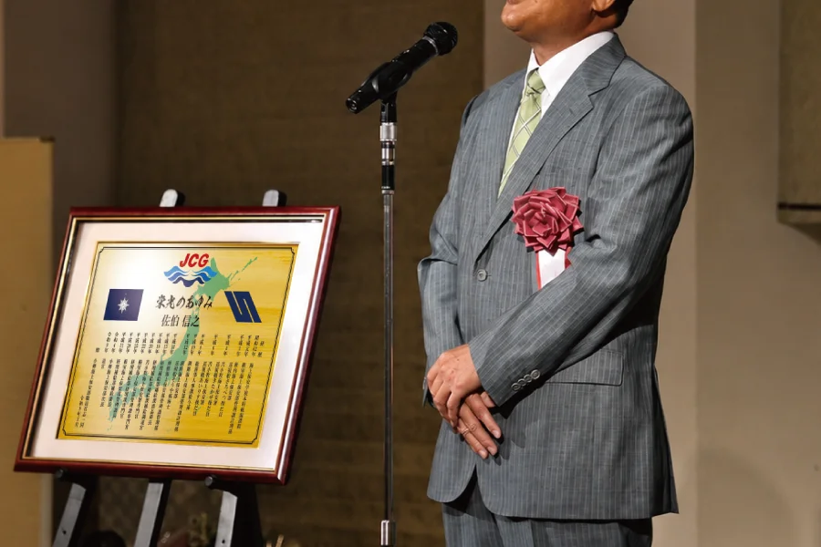 海上保安官が贈られた退官祝い記念品を前に挨拶する場面