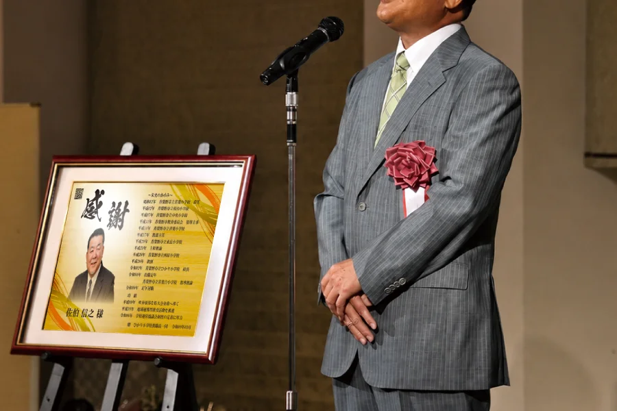 退職する学校の先生が教え子から退職記念品を受け取る場面