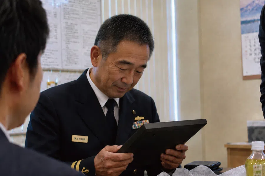 自衛官の退官祝い記念品を手に取り見つめる場面