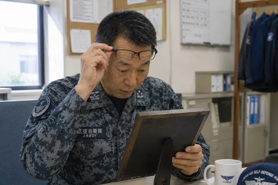 自衛官としての歩みを刻んだ記念品を注意深く見る場面